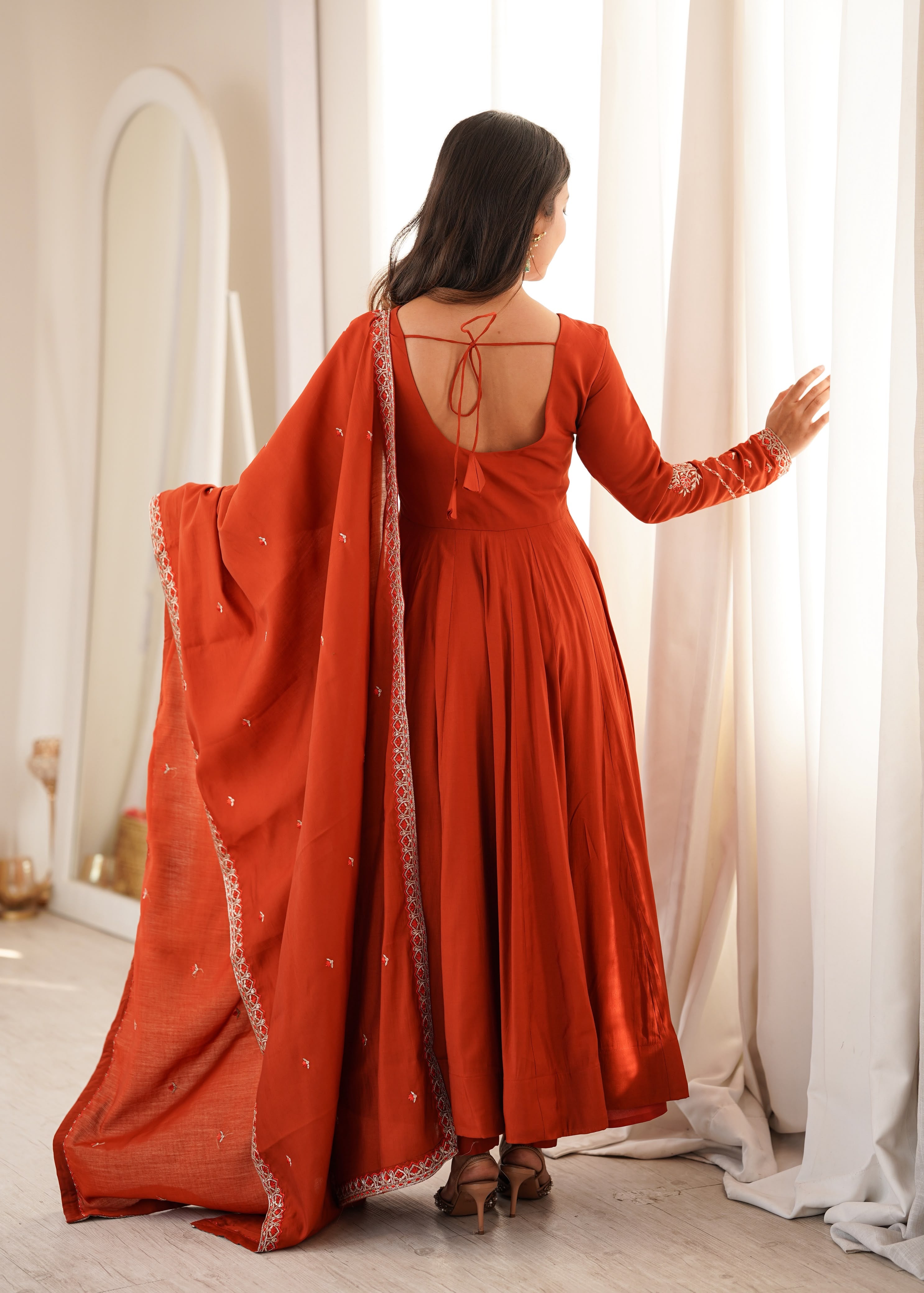 Draped in earthy rust and delicate embroidery.