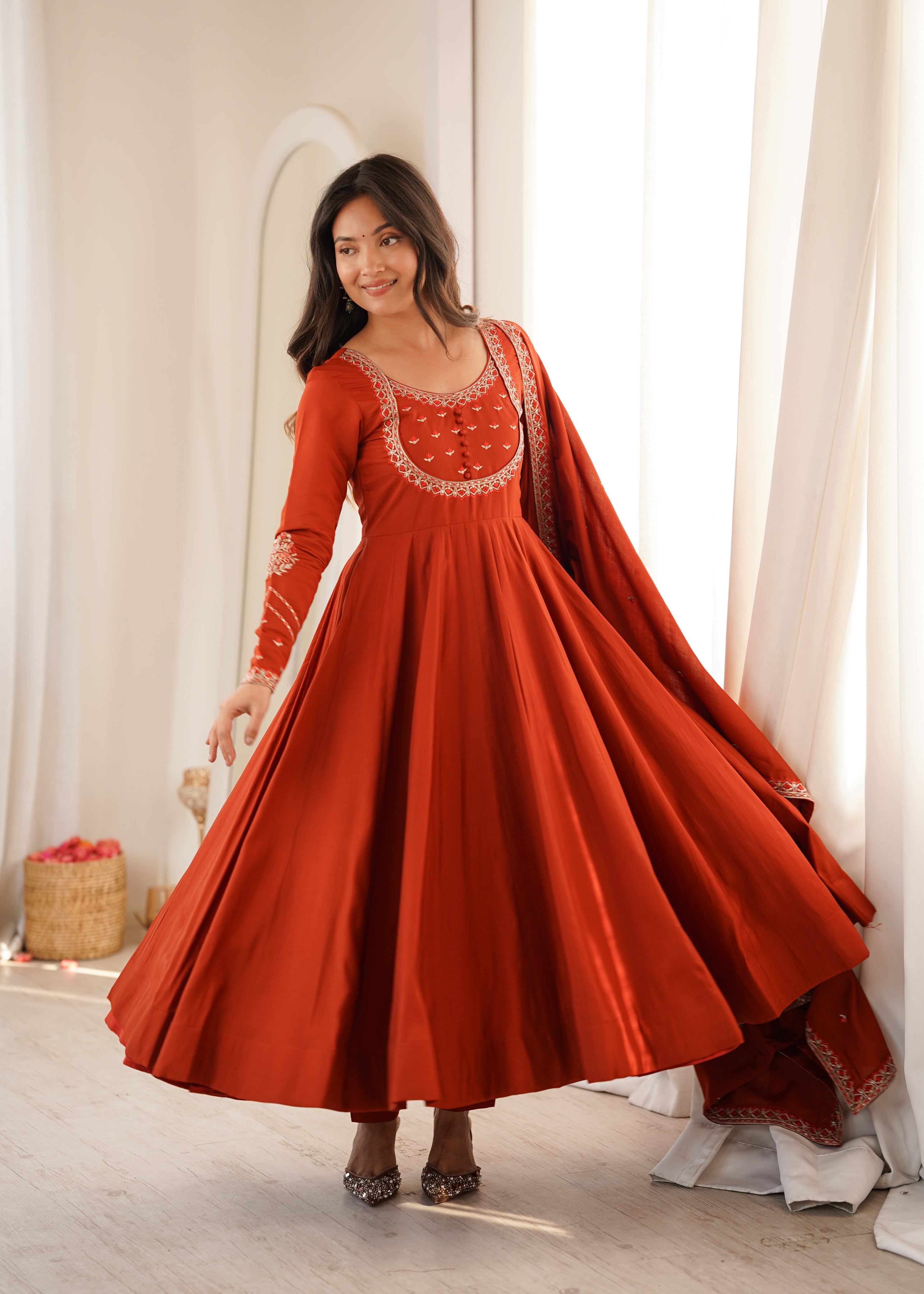 Draped in earthy rust and delicate embroidery.