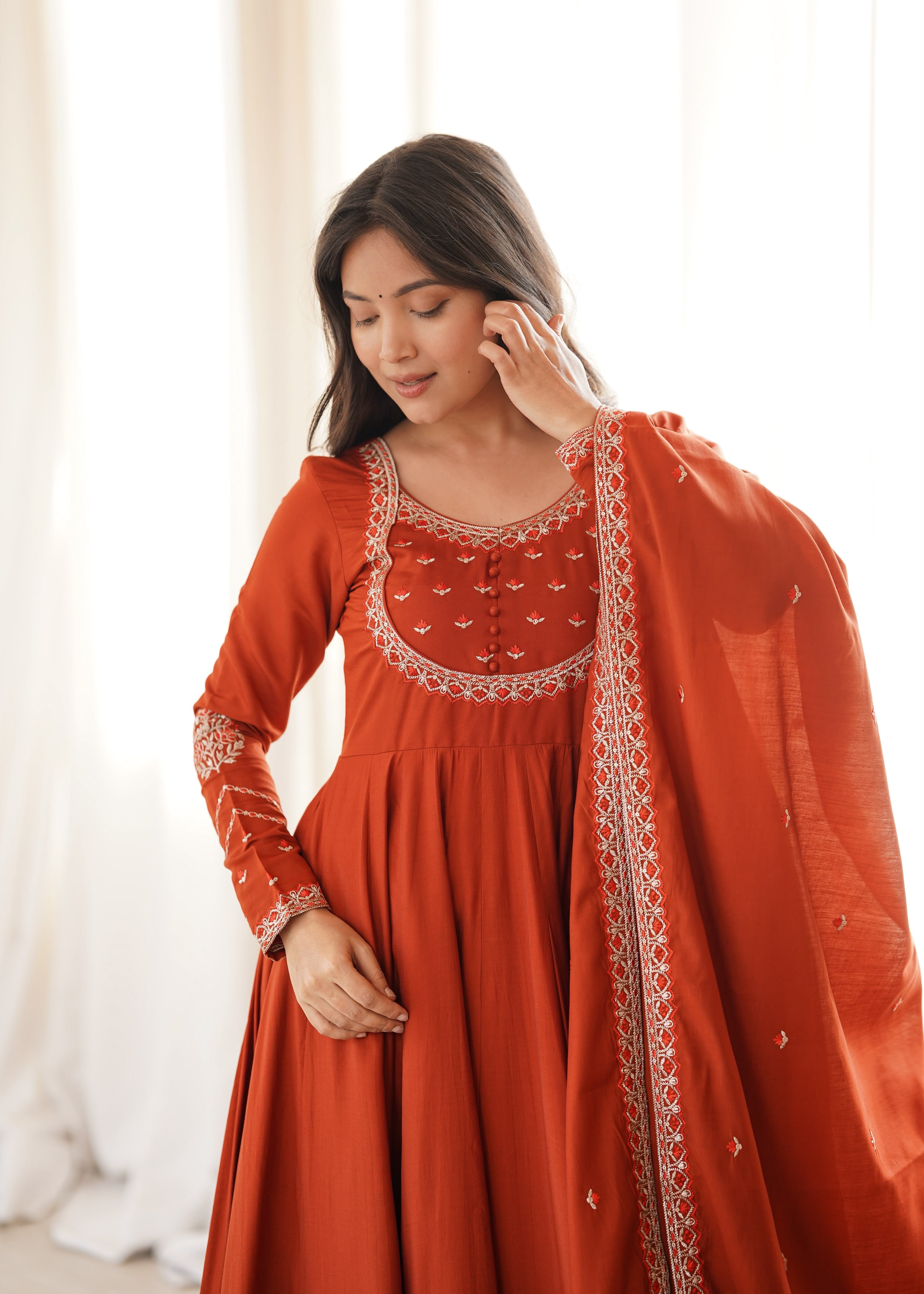 Draped in earthy rust and delicate embroidery.