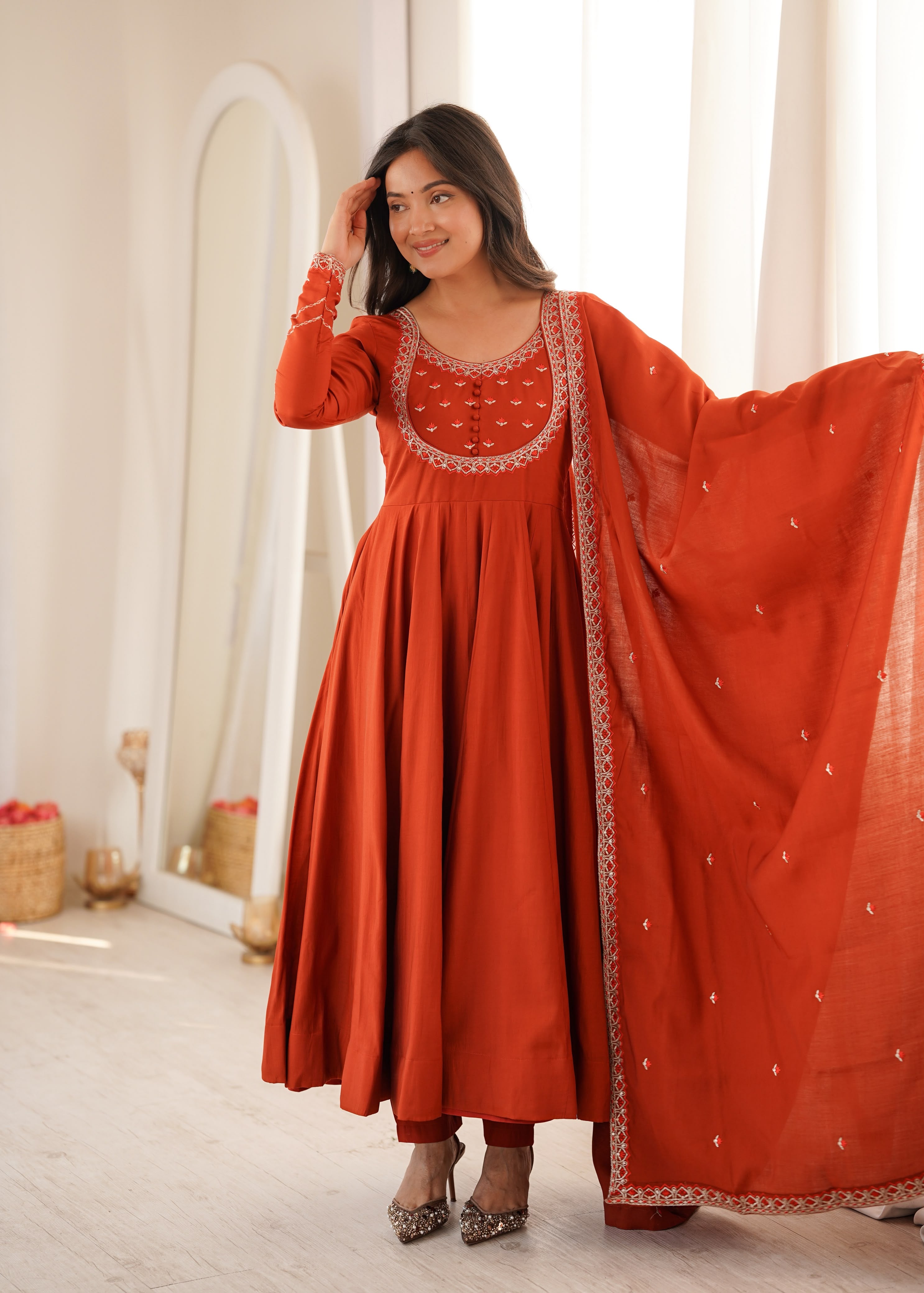 Draped in earthy rust and delicate embroidery.